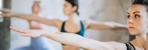 Group Yoga Classes 2 Women doing yoga and holding hands in the air